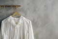 white blouses on gold hooks, soft grey wall background