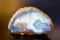 White blue agate gem cross section with reflection on dark colored background Royalty Free Stock Photo