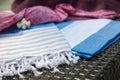 A white, blue and beige Turkish peshtemal / towel, pink bikini top, straw hat and white seashells on rattan lounger as background. Royalty Free Stock Photo