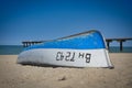 White and blue boat flipped on a sandy beach against a blue sky Royalty Free Stock Photo