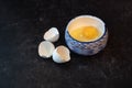 White and blue ceramic bowl with whole cracked egg white and yolk half eggshells next to bowl