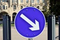 white and blue circular metal traffic sign on steel post in closeup view. white directional arrow. Royalty Free Stock Photo