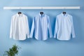 white and blue color men\'s long-sleeved shirts, blue tones, hanging on the wall, blue background, Generated AI Royalty Free Stock Photo