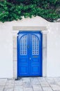 White blue decoration of windows and doors. A bright blue door set against a vintage-looking white fence in the city