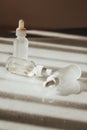 White and blue face serum and face oil bottles with droppers on white reflective tavle with water drops and light and shadow