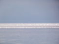 White, blue and grey bokeh effect and purposely blurred view of sea or ocean landscape. Blurry and shiny water and sky background
