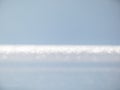 White, blue and grey bokeh effect and purposely blurred view of sea or ocean landscape. Blurry and shiny water and sky background
