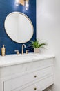 A white and blue half bathroom with gold accents.