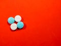 A white and blue medicine pills on red background. Royalty Free Stock Photo