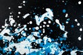 White and blue paint splatter on black background, abstract texture Royalty Free Stock Photo