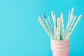 White and blue paper drinking straws with golden star polka dot pattern in stacked pink cups. Zero waste nature friendly