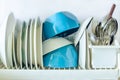 White and blue plates for eating, cutlery forks, knives, spoons in a glass for drying dishes in the kitchen on a white background