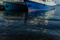 White blue ships boats bottoms on pier in bay of lake baikal with reflections in water in light of sun Royalty Free Stock Photo