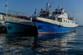 White blue ships boats on pier in bay of lake baikal with reflections in water  in light of  sun Royalty Free Stock Photo