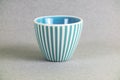 White with blue stripes deep porcelain bowl with shadows on a gray blurred background Royalty Free Stock Photo
