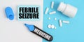 On the white and blue surface are pills, a marker and paper with the inscription - FEBRILE SEIZURE Royalty Free Stock Photo