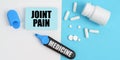 On the white and blue surface are pills, a marker and paper with the inscription - JOINT PAIN Royalty Free Stock Photo