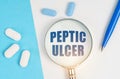 On a white and blue surface are pills, a pen and a magnifying glass with the inscription - Peptic ulcer