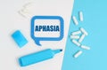 On a white and blue table are pills, a marker and a blue plaque with the inscription - aphasia Royalty Free Stock Photo