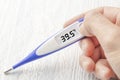 White-blue thermometer with a high temperature of 39.5 degrees Celsius in hand Royalty Free Stock Photo