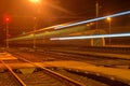 White and blue train passing a small roofless train station at night in the Czech Republic. Blurred motion train Royalty Free Stock Photo