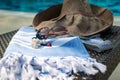 A white and blue Turkish towel, sunglasses, bikini and straw hat on rattan lounger with blue swimming pool as background. Royalty Free Stock Photo