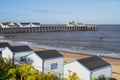 White and blue wooden beach huts along a sandy beach in Southwold. The pier is in the background Royalty Free Stock Photo