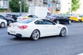 White BMW 640i F13 coupe car on the road in motion. Fast speed drive on city road. Rear side view of moving premium car on the Royalty Free Stock Photo