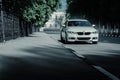 White BMW 3 Series F30 car standing on empty asphalt road at summer daytime Royalty Free Stock Photo