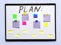 White board with a plan and colored sheets of paper for notes, on a light wall Royalty Free Stock Photo