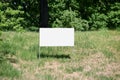 White board set on the ground with green grass against the background of trees and bushes outside on a summer day Royalty Free Stock Photo