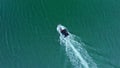 A white boat with a canopy floats in the middle of the sea, aerial view