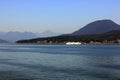 a white boat is in the middle of the water with mountains behind it