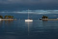 White boat sailing on a dark blue sea with small islands around under a stormy sky full of clouds Royalty Free Stock Photo