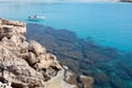 White boat and transparent blue sea near the rocky shore in Cyprus Royalty Free Stock Photo