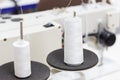 White bobbins of thread on sewing machine overlock close-up.