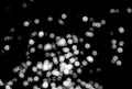 White bokeh on a black background closeup, bright glare of light texture, light lights, black and white photo