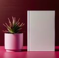 A white book sitting next to a pink plant in a pink pot