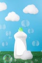 White bottle with dishwashing gel and place for your logo on a blue background with clouds of foam and soap bubbles.