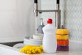 A white bottle with dishwashing gel, sponges and rubber gloves on the background of a sink with dirty dishes. Copy space Royalty Free Stock Photo