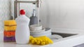 A white bottle with dishwashing gel, sponges and rubber gloves on the background of a sink with dirty dishes. Copy space Royalty Free Stock Photo