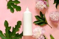 A large white plastic bottle with place for your text on a pink background with green leaves of plants Royalty Free Stock Photo