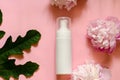 White bottle with place for your text on a pink background with flowers and leaves Royalty Free Stock Photo