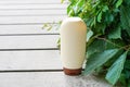 White bottle with shampoo or lotion staying on the wood with green leaves background