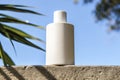 A white bottle with a white cap sits on a ledge in the sun Royalty Free Stock Photo