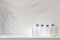 White bottles with blue dispenser with shampoo, conditioner, cream and liquid soap stand on a shelf in the bathroom. Place for Royalty Free Stock Photo