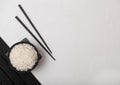 White bowl with boiled organic basmati jasmine rice with black chopsticks on bamboo place mat on white background. Space for text Royalty Free Stock Photo