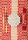 White bowl with boiled organic basmati jasmine rice with wooden chopsticks and sweet soy sauce on bamboo placemat background Royalty Free Stock Photo