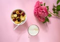 A white bowl of cereal with a tiny pancake with cherries, a cup of cappuccino and flowers on a pink background. Top view. Royalty Free Stock Photo