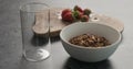 White bowl with chocolate granola, strawberries and glass for yogurt on a concrete countertop Royalty Free Stock Photo